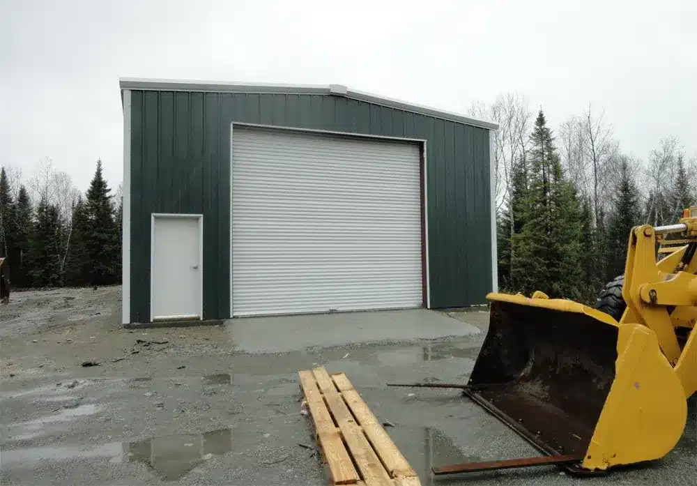 Green steel workshop with roll-up door and walk-in entry.