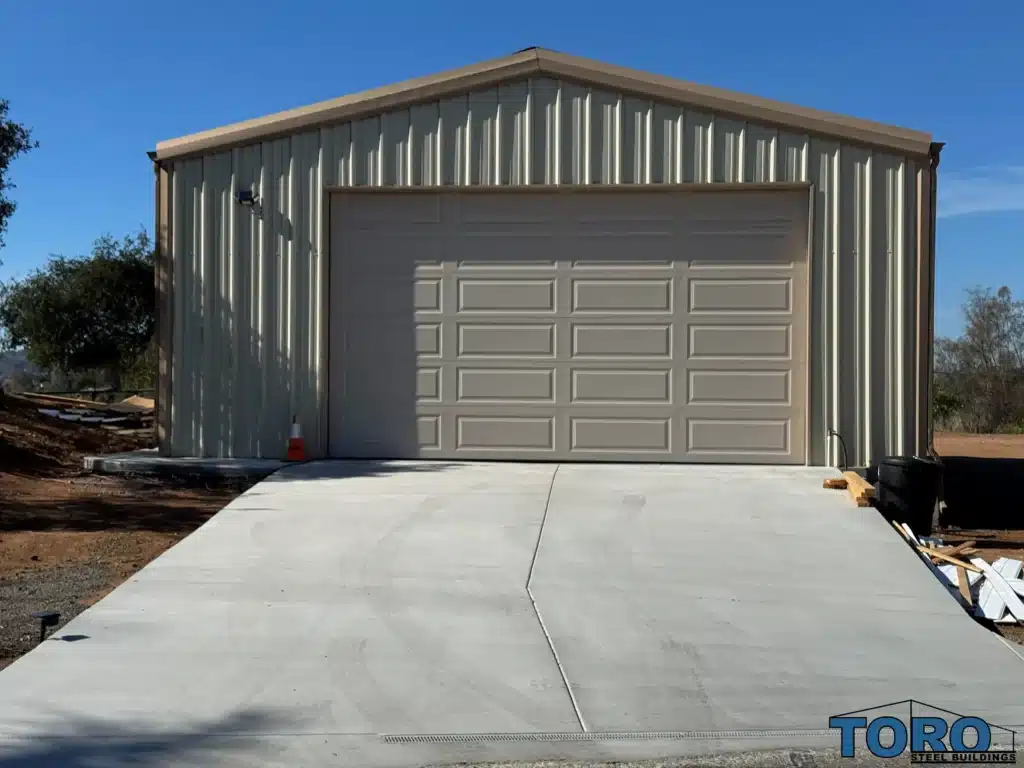 Tan steel garage with gable roof and roll-up door.