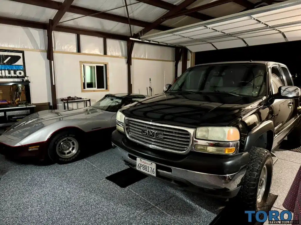 Black GMC truck and Corvette inside steel garage.